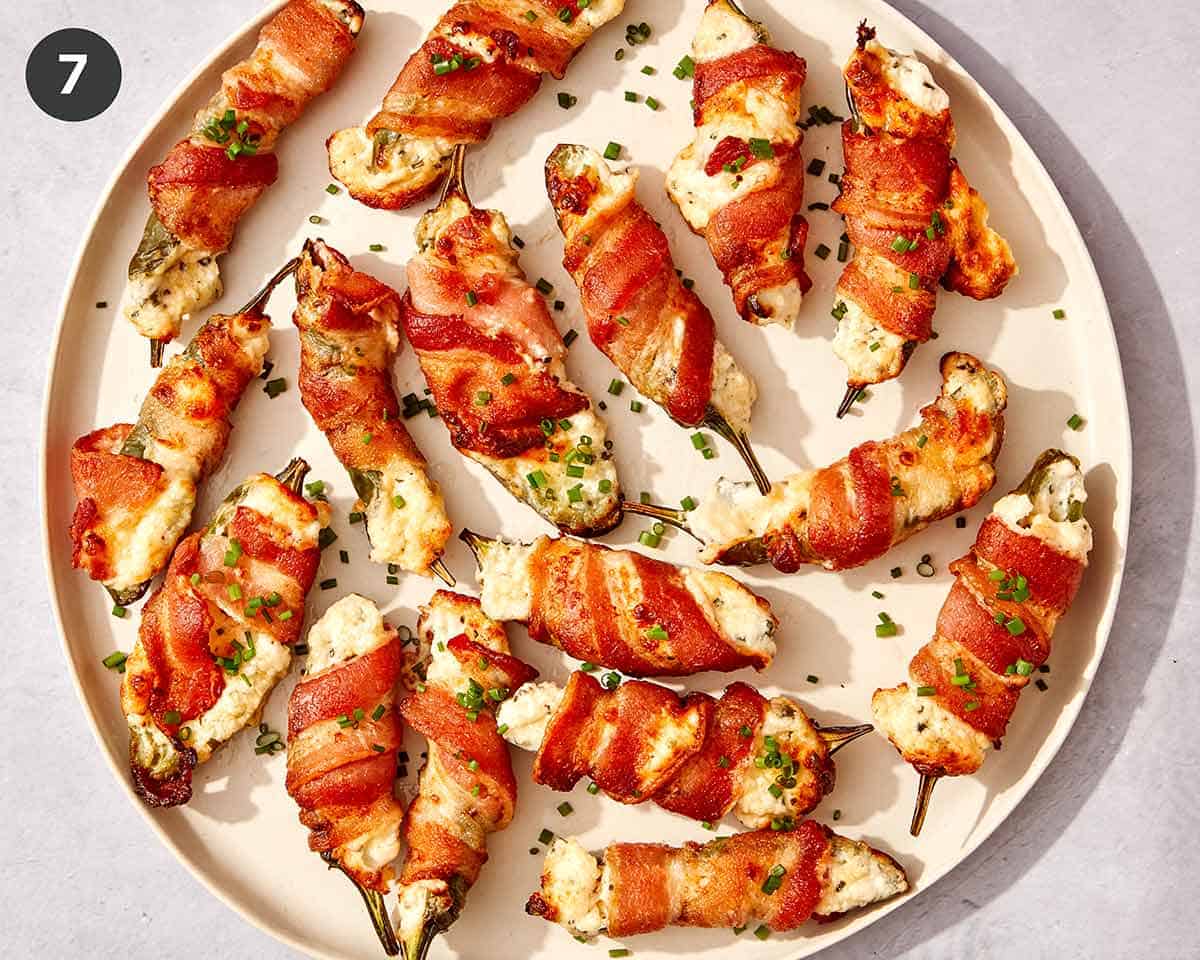 Jalapeno poppers on a platter with chives on top.
