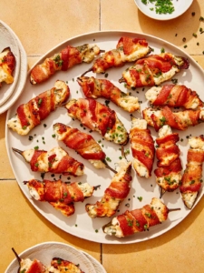 A platter full of jalapeno poppers with some on plates.