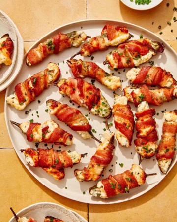 A platter full of jalapeno poppers with some on plates.