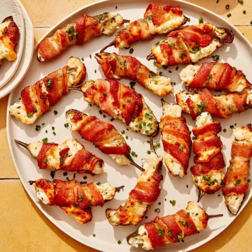 A platter full of jalapeno poppers with some on plates.