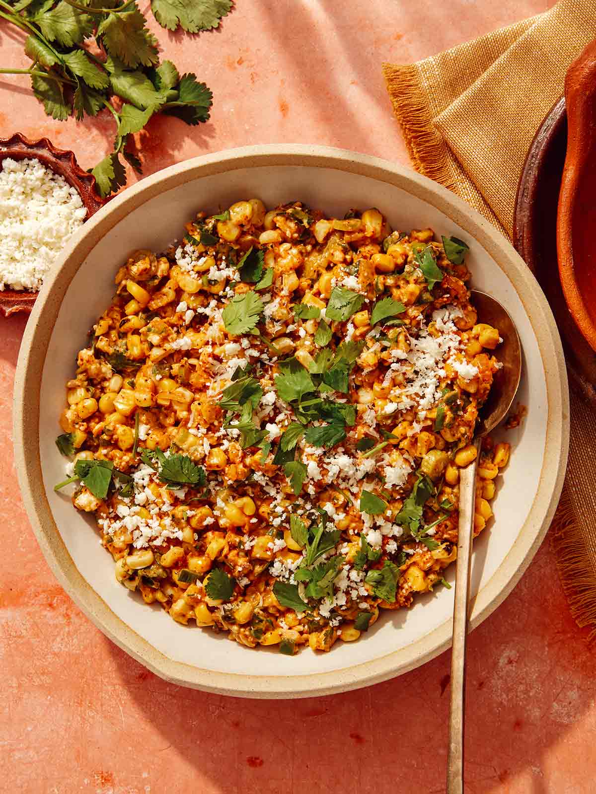 Mexican street corn salad in a bowl with a spoon in it.