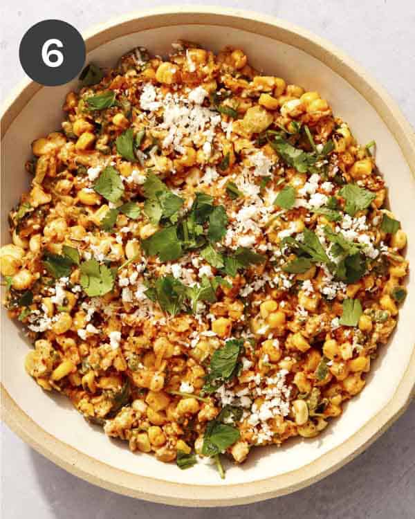 Mexican street corn salad in a bowl with cilantro and cheese on top.