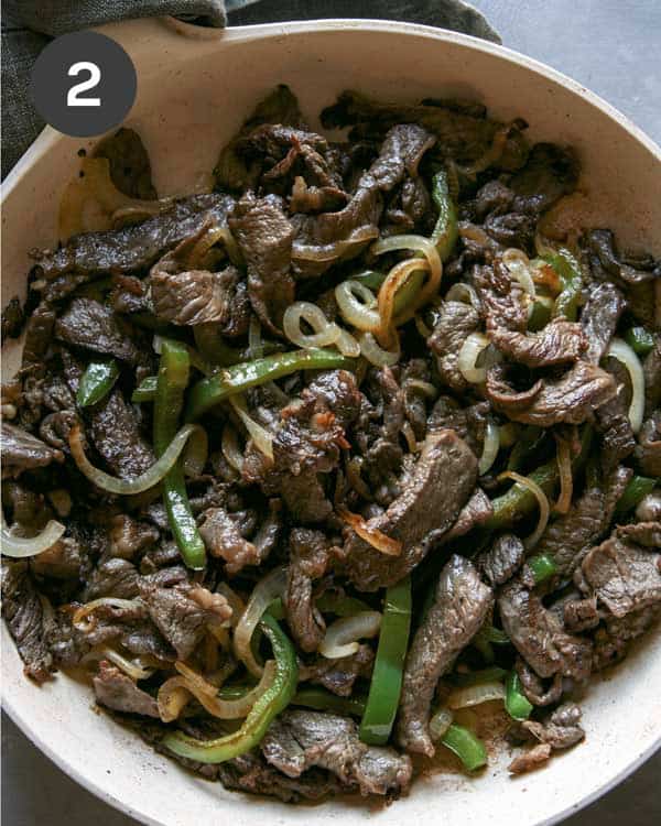 Philly Cheesesteak cooking in a skillet.