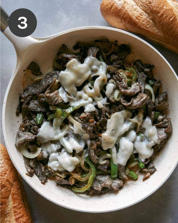 Philly cheesesteak in a skillet with melted cheese.