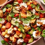 Panzanella salad in a bowl with fresh herbs on top.