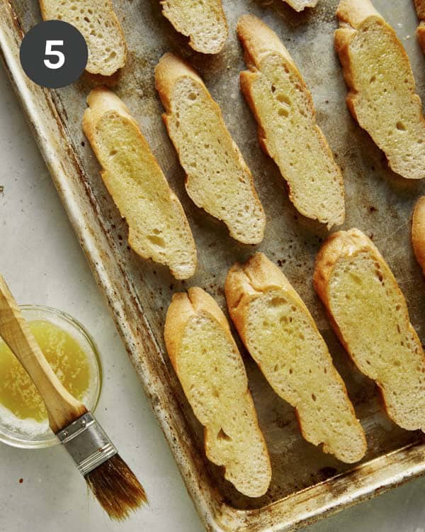 Brushing sliced baguettes with olive oil for bruschetta.