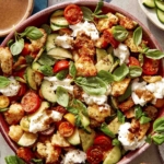 Panzanella salad in a bowl with fresh herbs next to it.