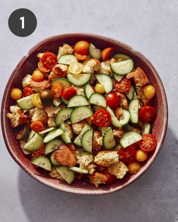 Ingredients of panzanella salad in a bowl ready to be tossed with dressing.
