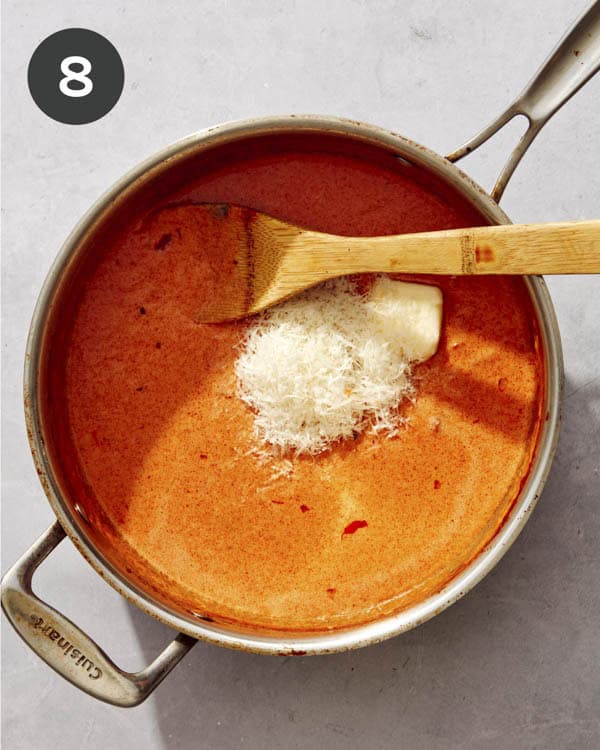 Creamy tomato sauce with cheese being added to the pan.