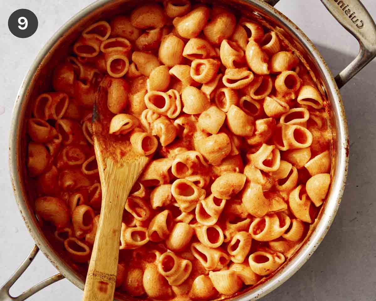 Pasta added to a pan with a creamy tomato sauce.