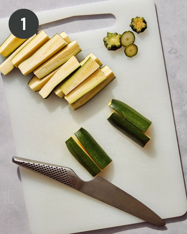Zucchini being trimmed and cut into wedges.