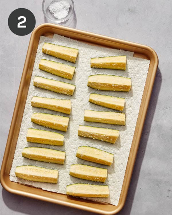 Zucchini wedges on a baking sheet with salt on them.