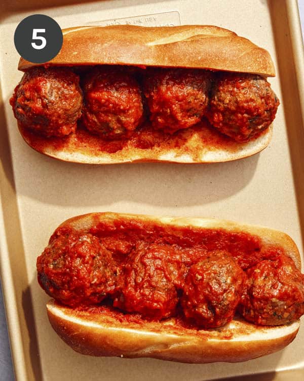 Meatball subs on a baking sheet ready for cheese.