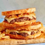 Two patty melt sandwiches on a cutting board.