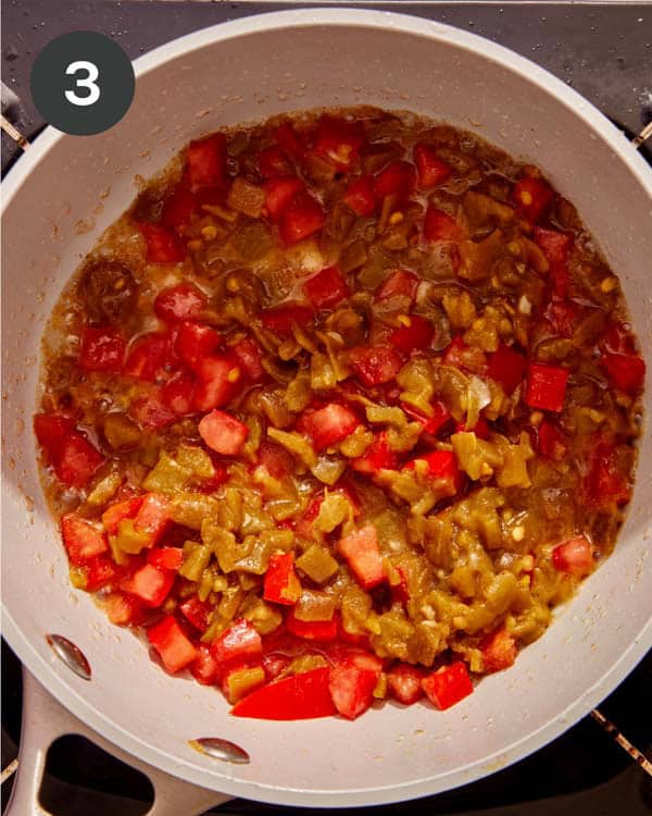 Peppers, tomatoes, and onions in a skillet with garlic cooking down to make queso.