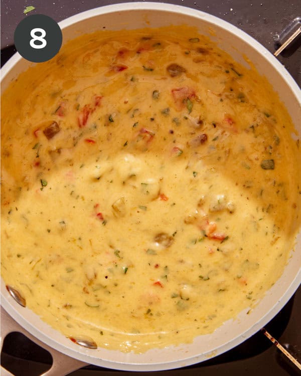 Cilantro mixed in to queso in a pot.