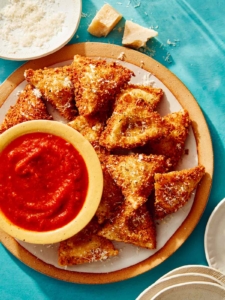 Toasted ravioli on a platter served with marinara sauce.
