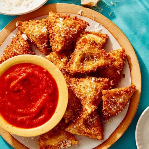 Toasted ravioli on a platter served with marinara sauce.
