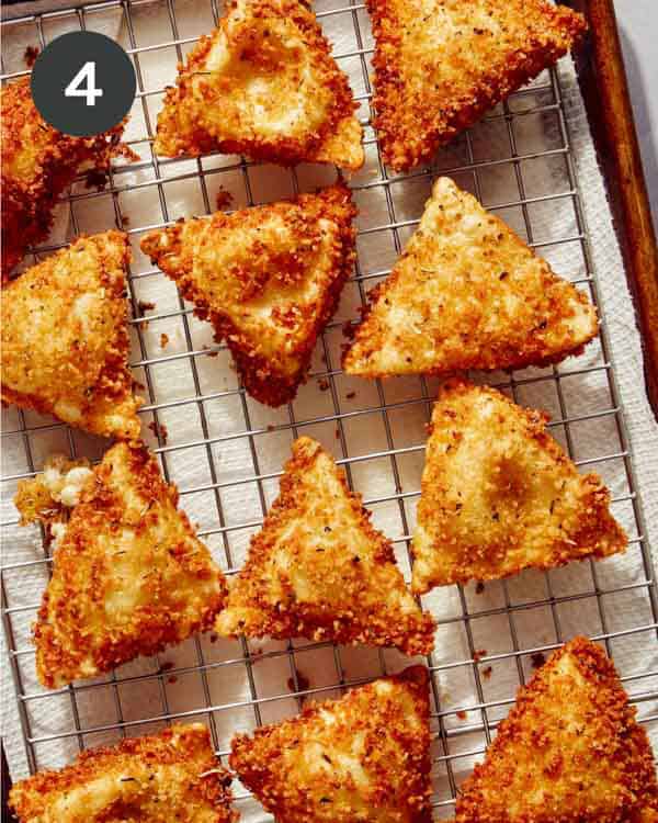 Freshly fried ravioli on a baking sheet.