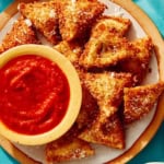 Toasted ravioli on a platter served with marinara sauce.