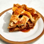A slice of apple pie on a plate with a fork next to it.