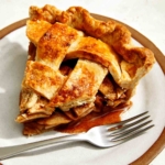 A slice of apple pie on a plate with a fork next to it.