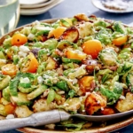 Shaved brussel sprout salad recipe in a bowl with a spoon.