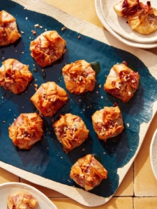 A brie appetizer recipe on a platter with plates on the side for serving.