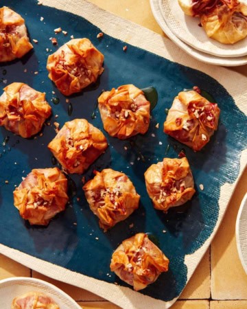 A brie appetizer recipe on a platter with plates on the side for serving.