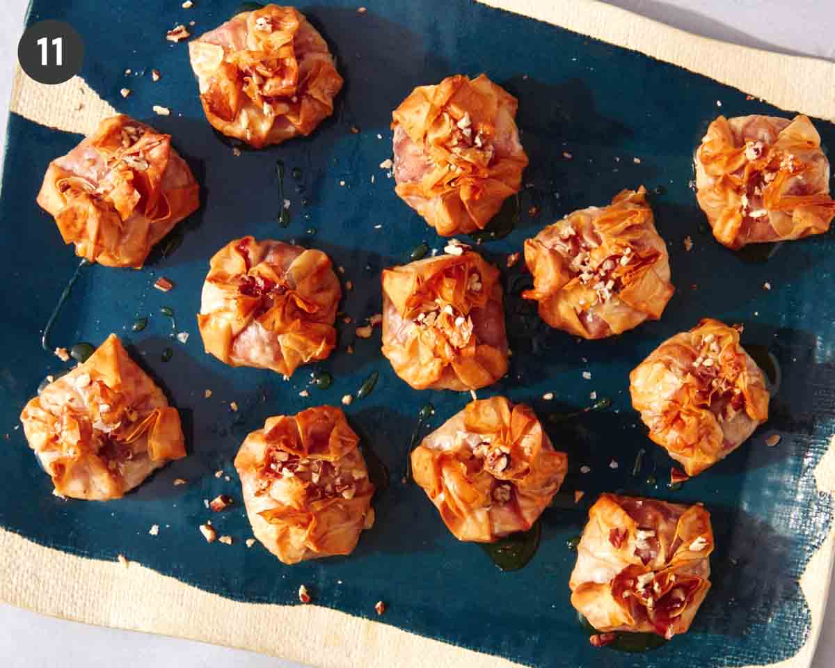 Crispy cranberry brie bites on a platter with honey and nuts.