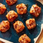 Crispy brie bites on a platter with honey and nuts.