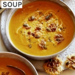 Pumpkin soup in a bowl with another bowl of soup peeking in.