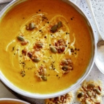 Two bowls of creamy pumpkin soup.