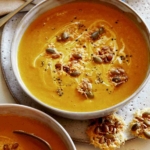 Two bowls of creamy pumpkin soup.