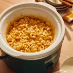 A crock pot filled with fresh macaroni and cheese.