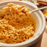 Crock pot mac and cheese with a spoon taking out a big scoop