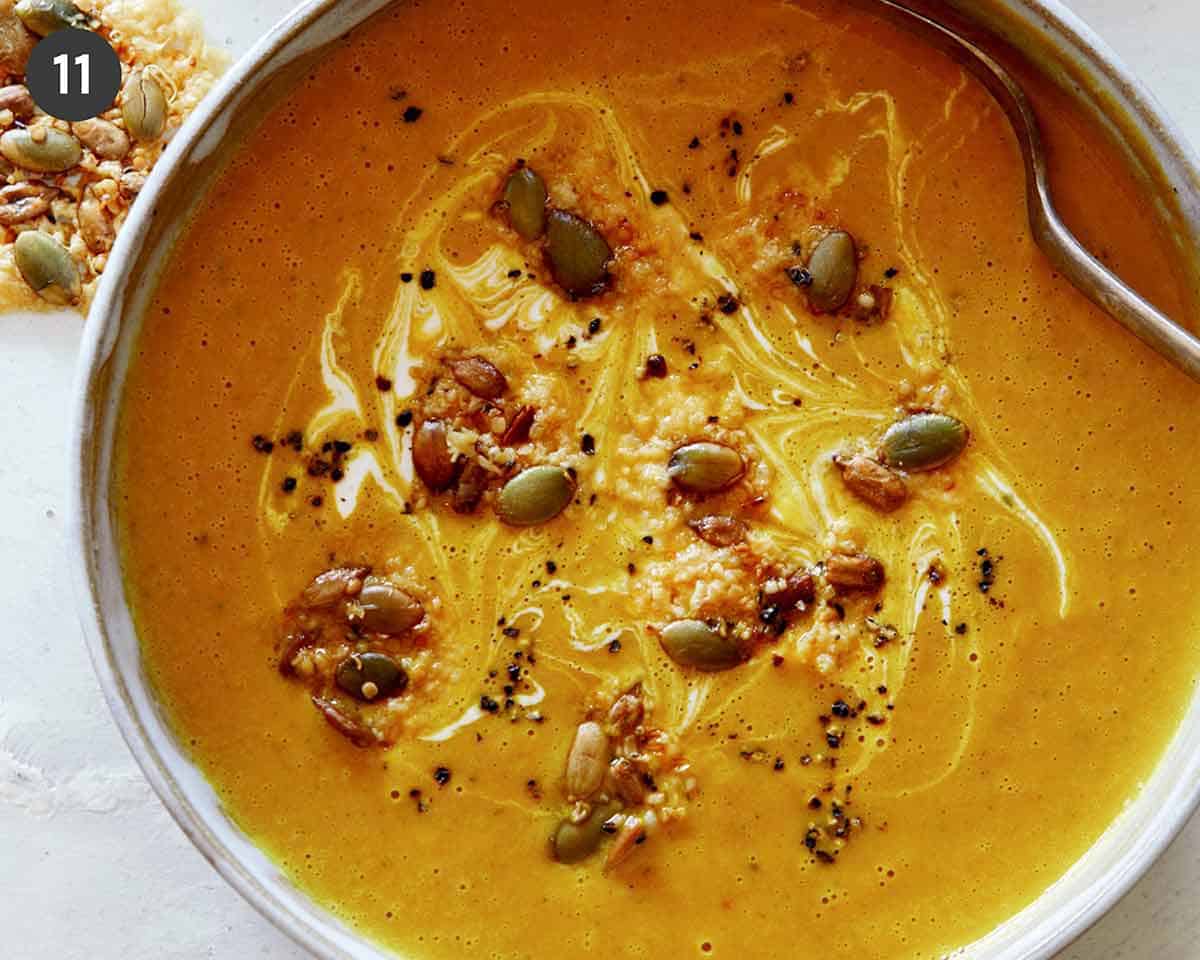 Creamy Pumpkin Soup recipe in a bowl with a spoon in it and parmesan crisps next to it, part of our Thanksgiving appetizers.