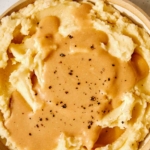 Roasted Garlic Gravy poured on a bowl of mashed potatoes.