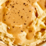 Roasted Garlic Gravy poured on a bowl of mashed potatoes.