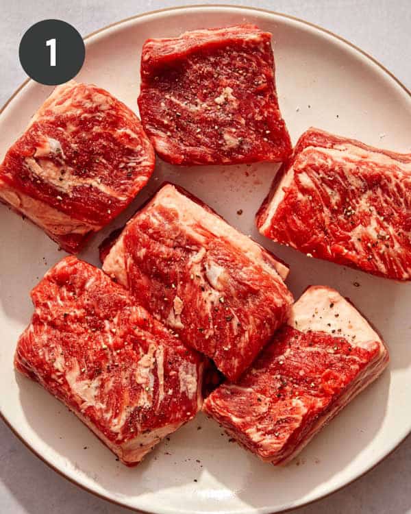 Short ribs on a plate with salt and pepper.