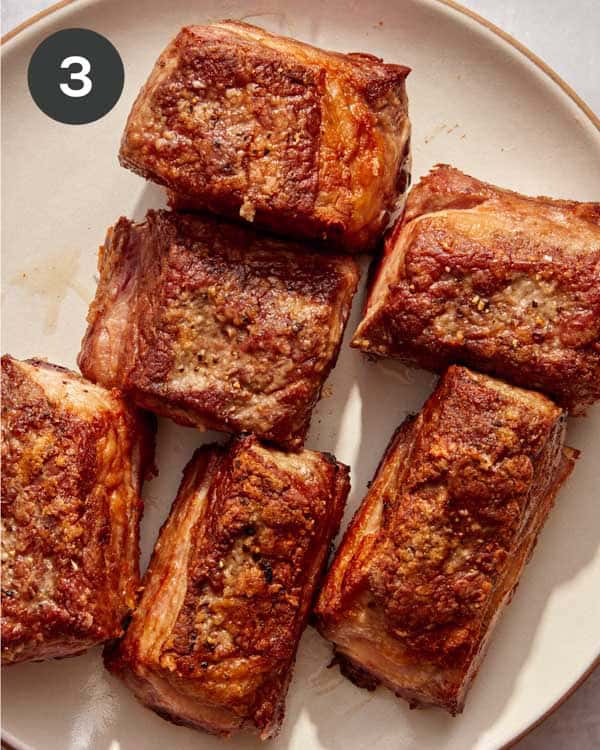 Seared short ribs resting on a plate.