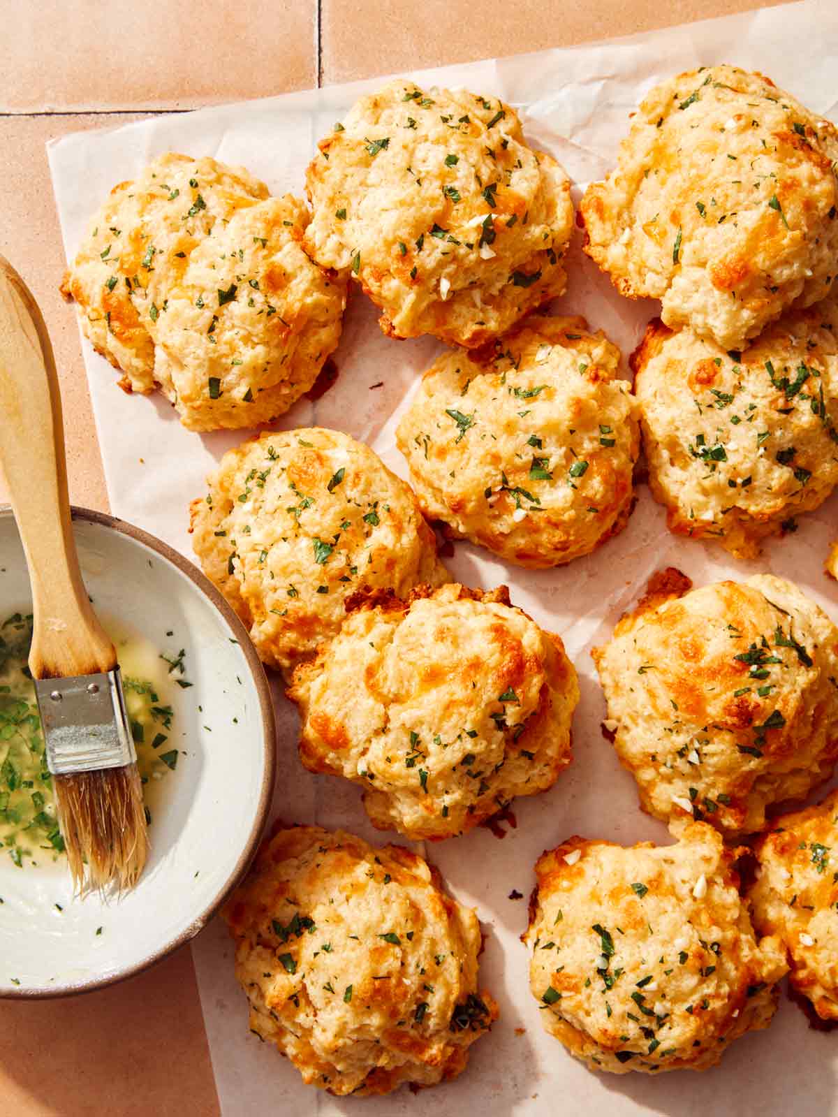 Cheddar bay biscuits on a surface with butter topping on the side. 