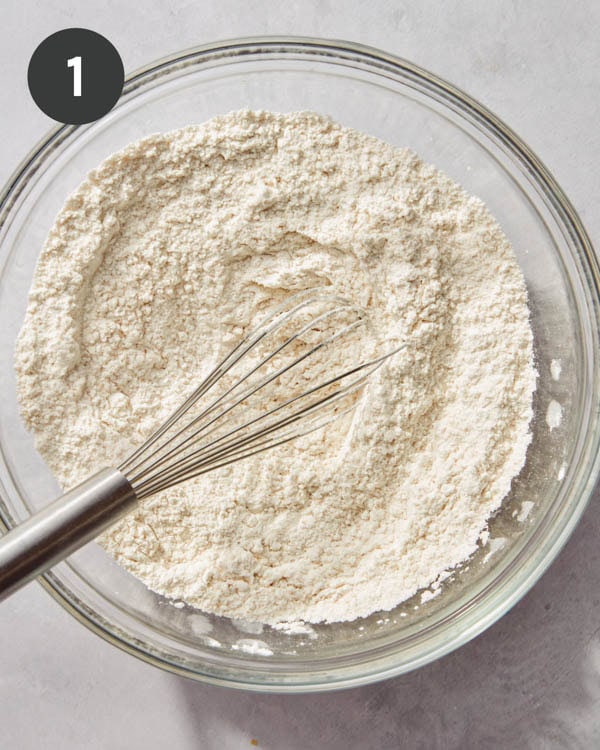 Flour mixture in a glass bowl with a whisk to make biscuits. 