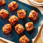 A brie appetizer recipe on a platter with plates on the side for serving.