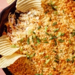 Jalapeño popper dip up close on the skillet with chips and drinks on the side.