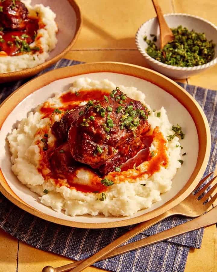Braised short ribs on top of mashed potatoes in a bowl.