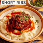 Braised short ribs on top of a bed of mashed potatoes in a bowl.