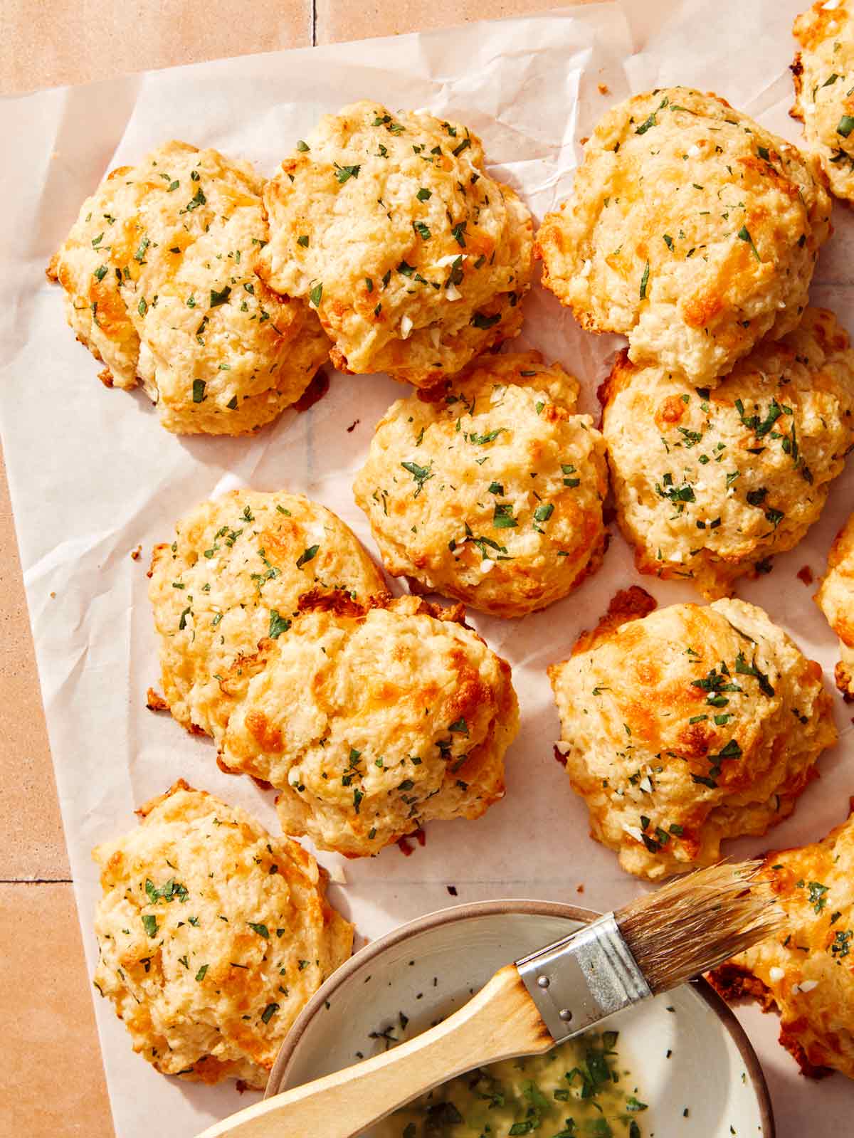 Cheddar bay biscuits on a piece of parchment paper all piled up.
