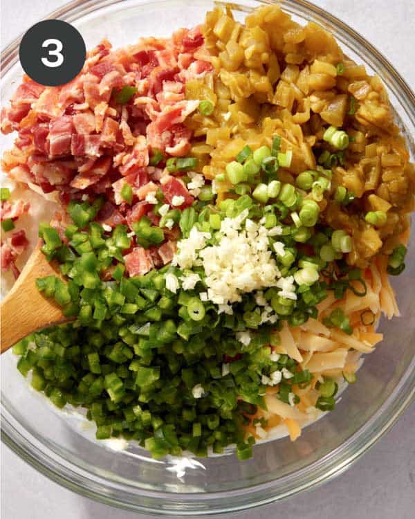 Jalapeño popper dip being mixed together in a glass bowl.
