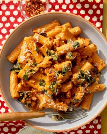 Close up on a bowl of kale and sausage rigatoni in a bowl with a fork.